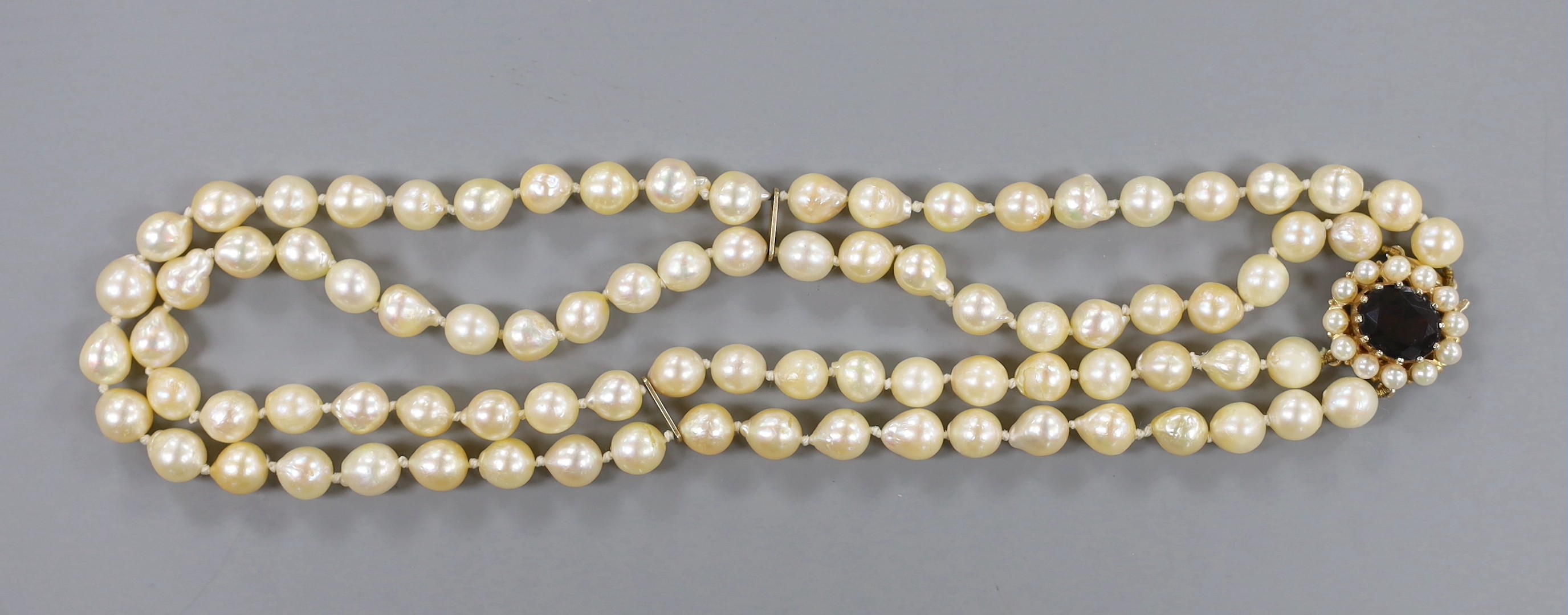 A twin strand cultured pearl necklace with a 9ct gold and garnet set clasp, 39cm.